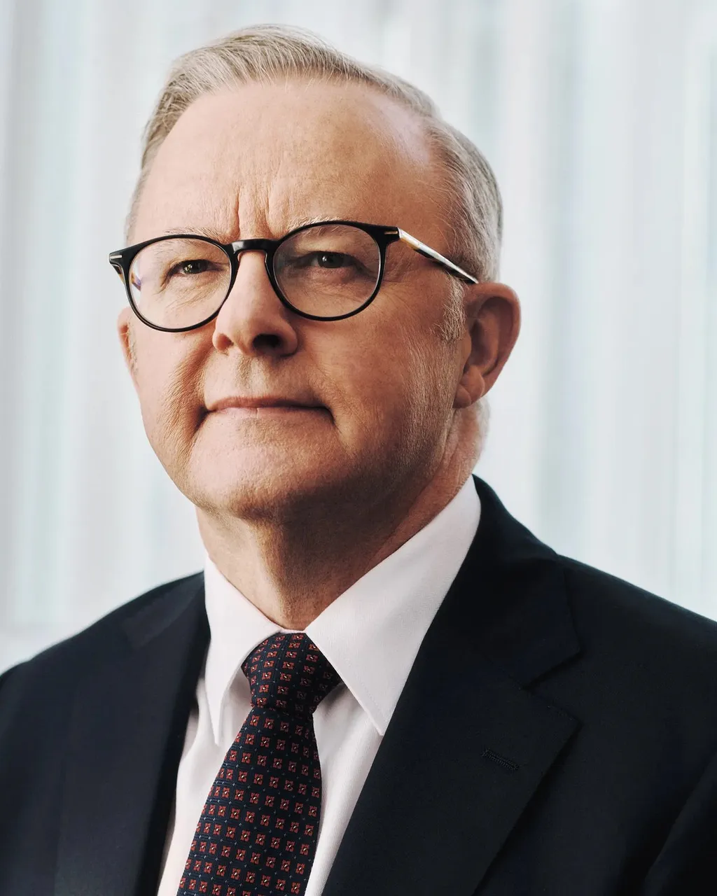 Official portrait of Australian Prime Minister Anthony Albanese, wearing glasses and a navy suit.