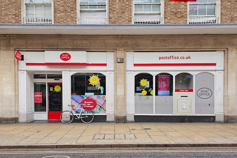 A UK Post Office branch storefront with red Post Office signage and postoffice.co.uk branding.