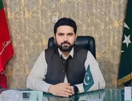 Sohail Afridi, the Khyber Pakhtunkhwa chief minister, seated at his office desk with a Pakistani flag