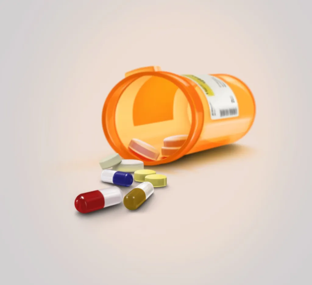 Spilled orange prescription pill bottle with assorted tablets and capsules on a white background.