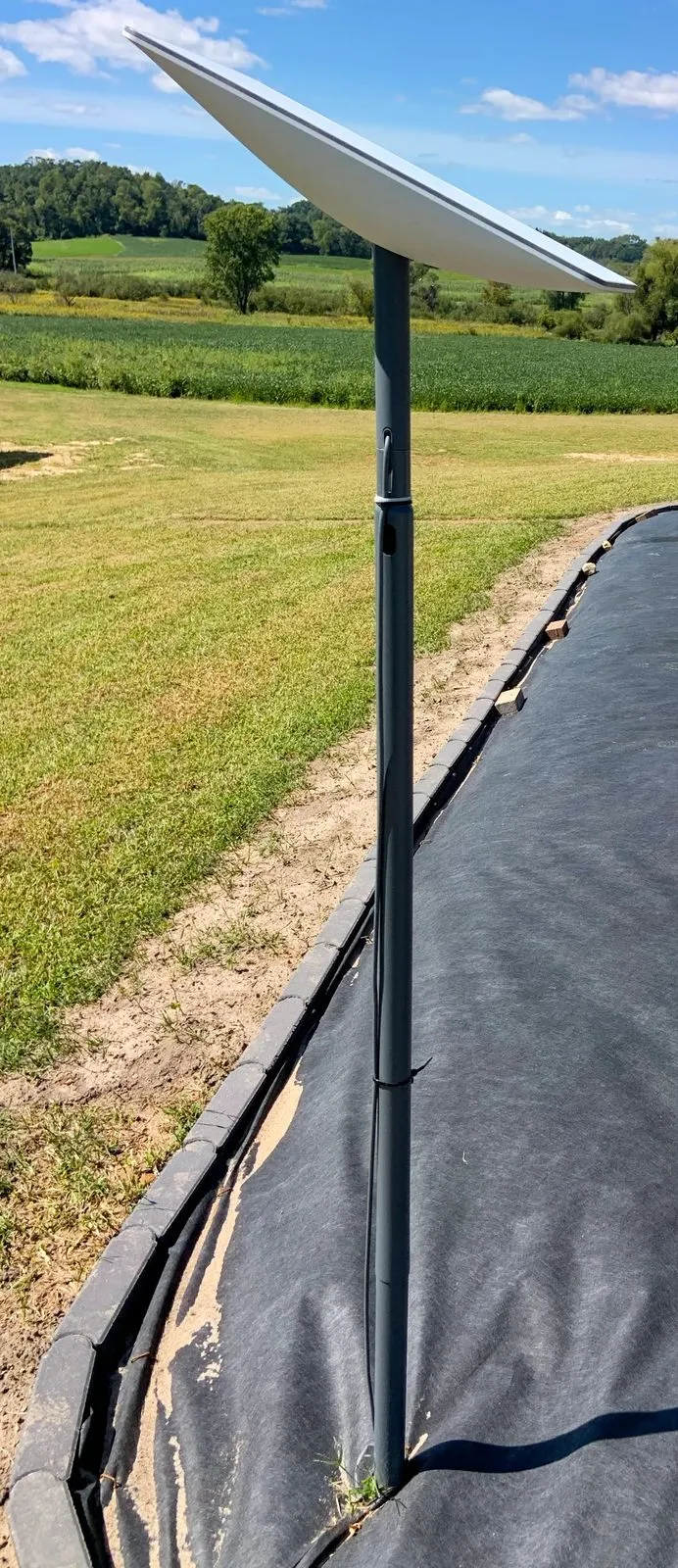 A Starlink user terminal dish mounted on a pole outdoors