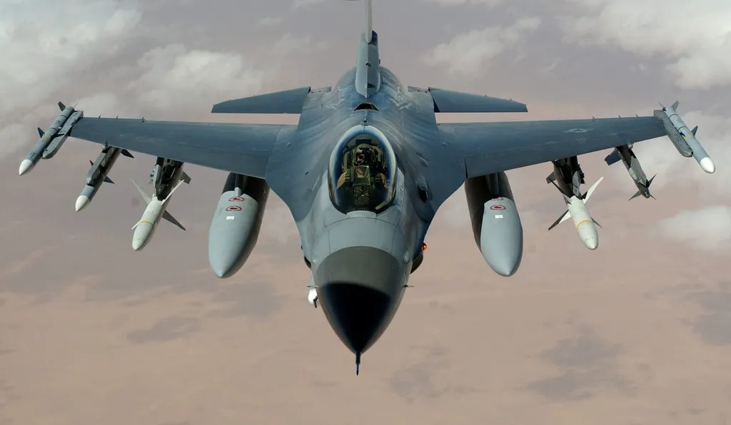 An F-16 Fighting Falcon in flight, armed with underwing missiles and drop tanks