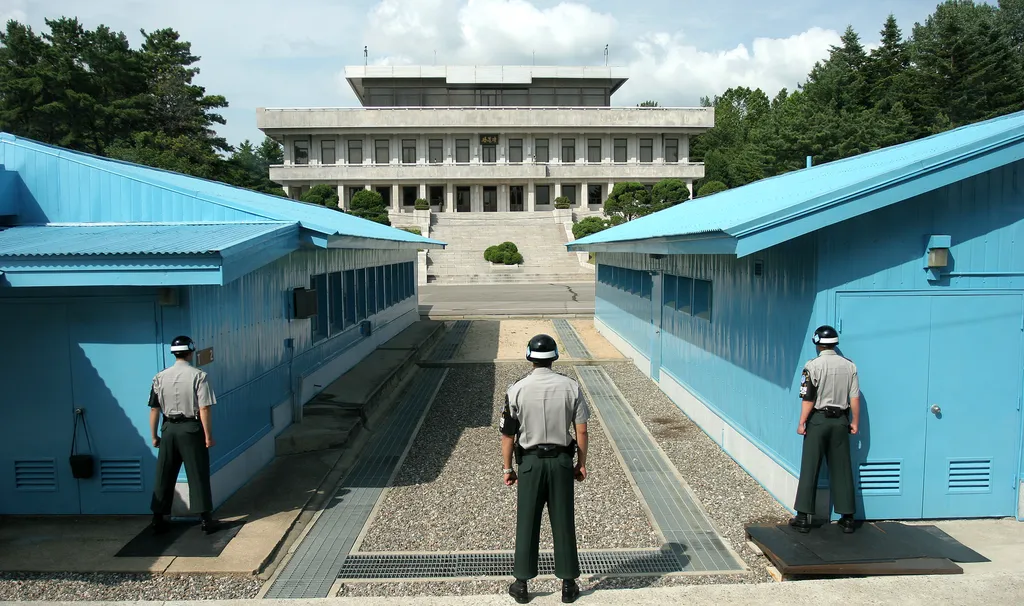 Three South Korean soldiers in green uniforms watching the border at Panmunjeom in the Demilitarized Zone