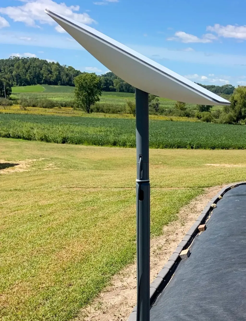 A Starlink satellite dish mounted on a pole in a grassy field.