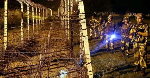 Indian BSF personnel patrol the border fence at night