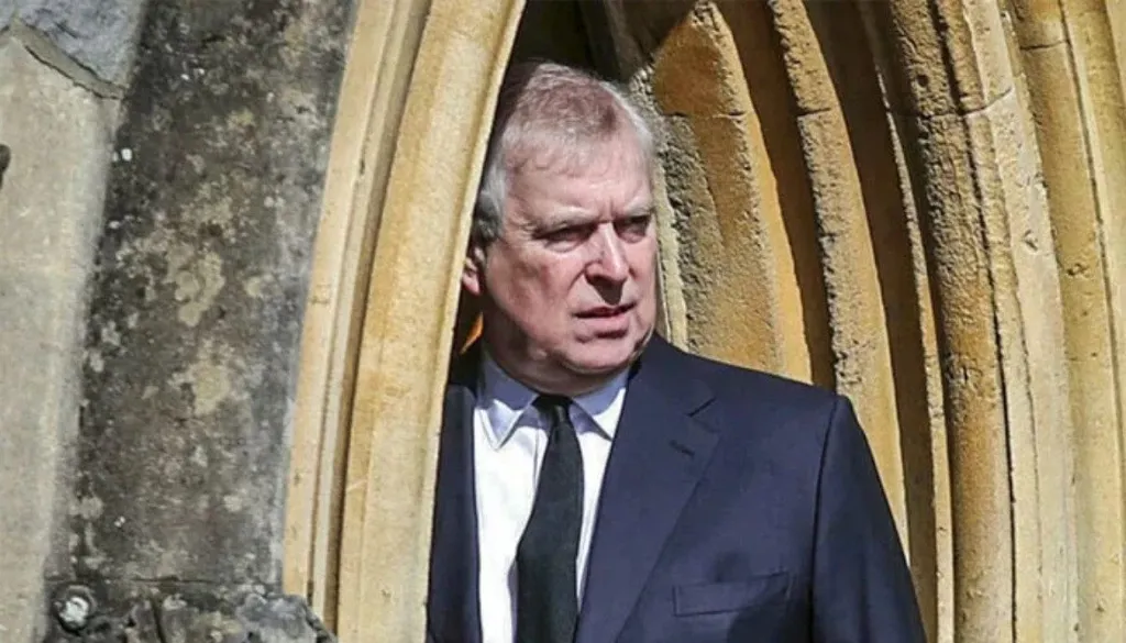 Andrew Mountbatten-Windsor standing in a stone doorway in a suit