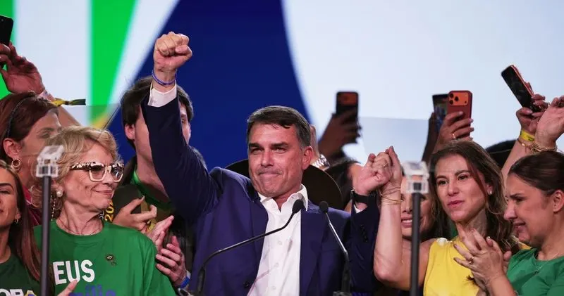 Flavio Bolsonaro raising his fist on stage as supporters celebrate his first-round election win