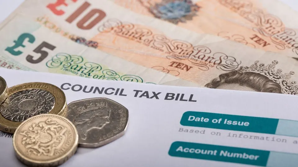 A UK council tax bill with pound notes and coins on top