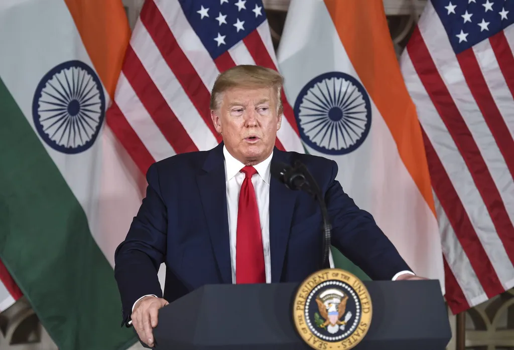 Donald Trump speaking at a podium with US and Indian flags behind him
