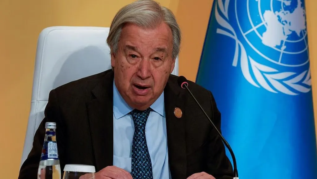 UN Secretary-General Antonio Guterres speaking at a press conference with a UN flag beside him
