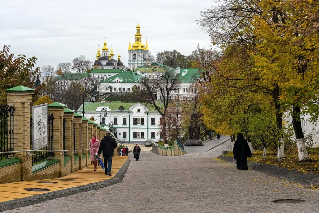 The golden domes of the Kyiv Pechersk Lavra rise above an autumn street in Kyiv, Ukraine