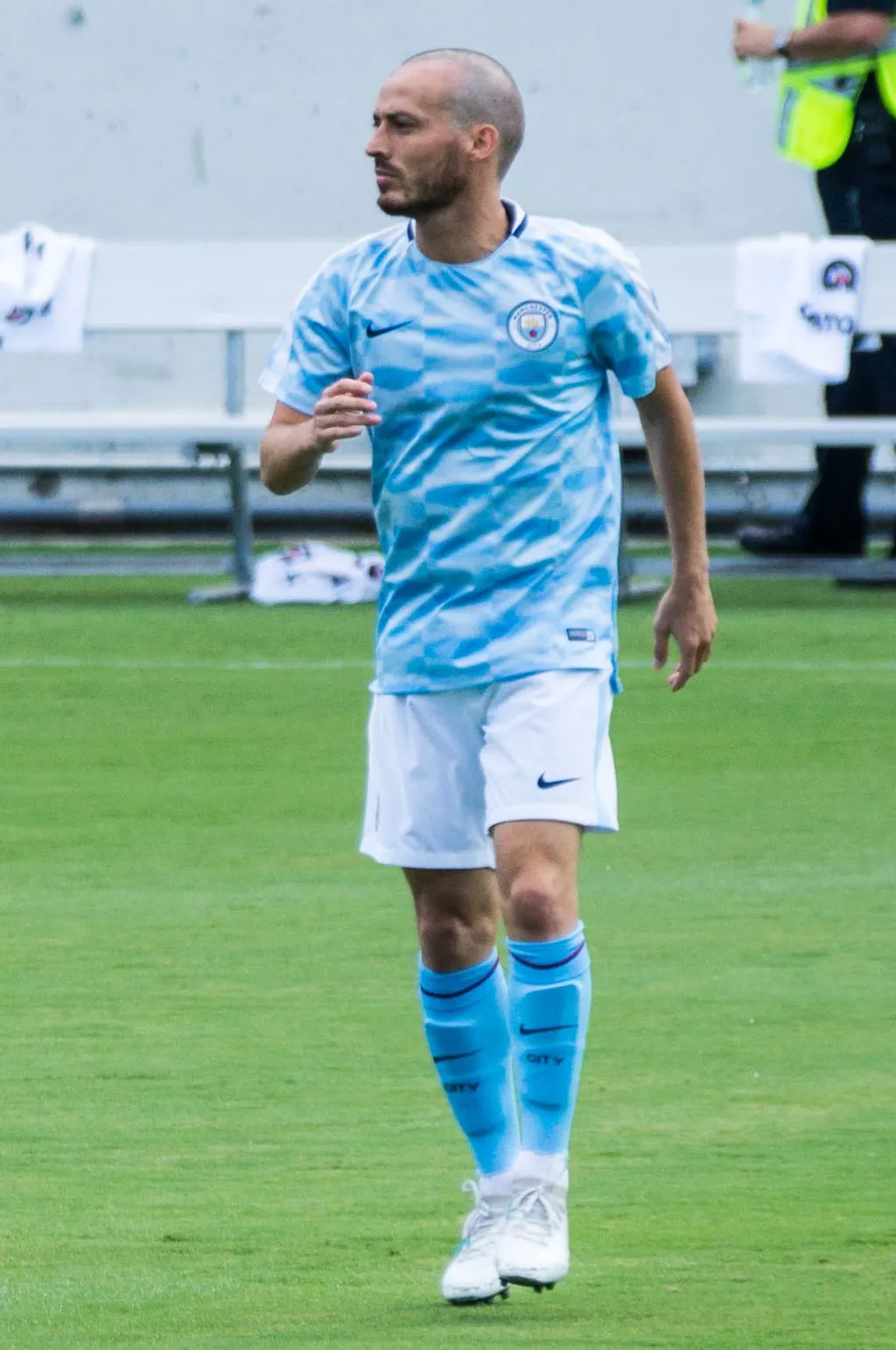 David Silva, bald, in a Manchester City sky-blue kit, running on a football pitch