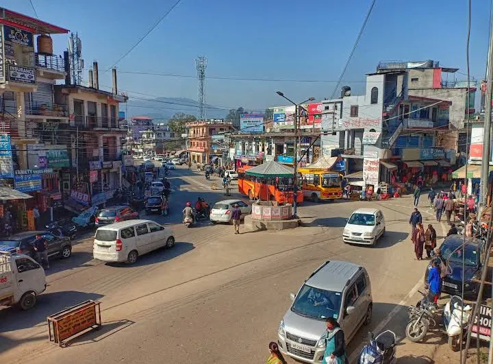 Busy street in Ghumarwin town, Bilaspur district, Himachal Pradesh, with vehicles, shops and hillside behind