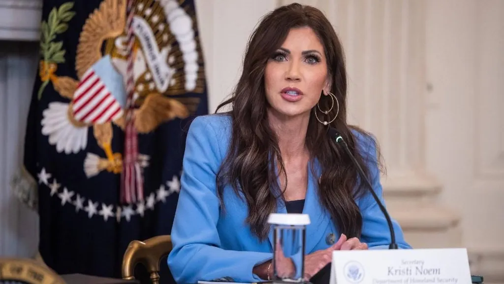 Kristi Noem seated at a White House meeting with a Department of Homeland Security secretary name placard