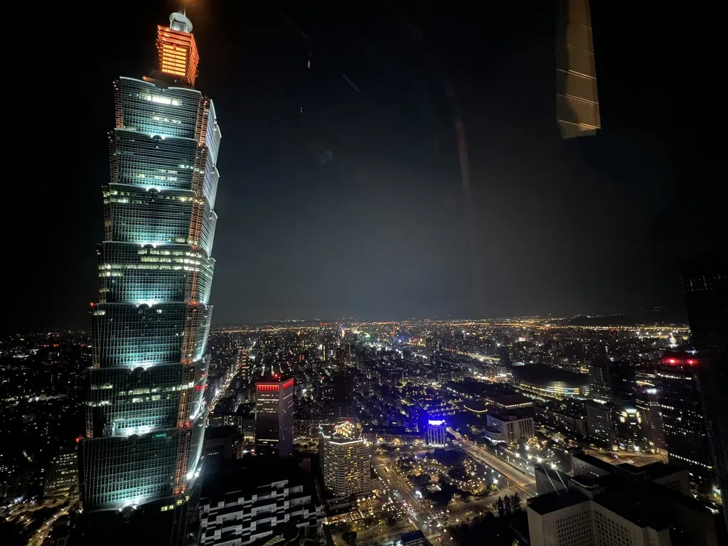 Taipei 101 illuminated at night, towering over the Taipei city skyline.