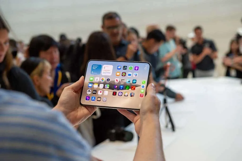 A person holding Apple's foldable iPhone Duo open at a hands-on event, showing the unfolded display with app icons