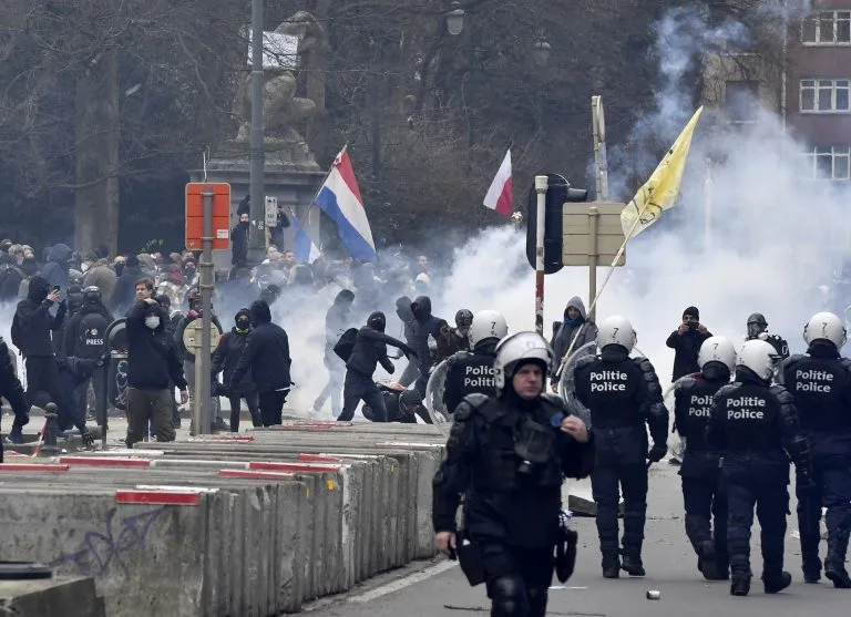 Belgian police in riot gear advance through tear gas during violent clashes with student protesters in Brussels