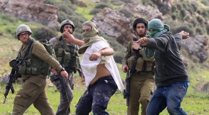 Masked settlers confronted by Israeli soldiers during a West Bank clash