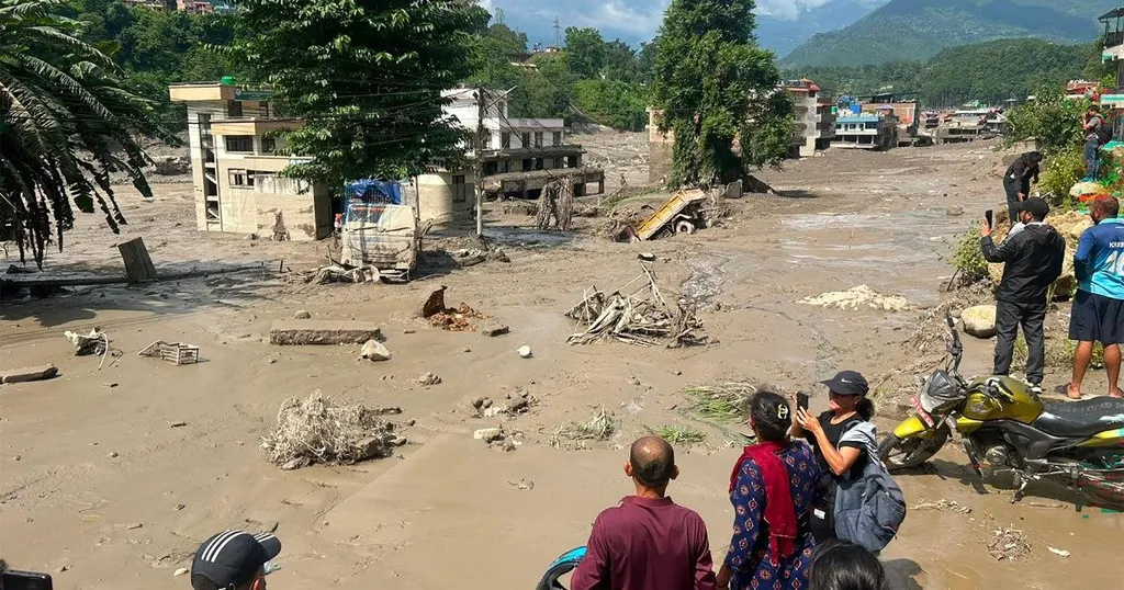 Muddy flash-flood aftermath in Nepal's Gorkha region with debris, damaged buildings and onlookers