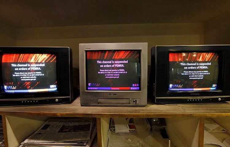 Television sets in Pakistan displaying PEMRA channel-suspension notices.