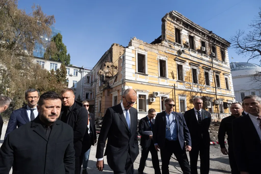 Ukrainian President Volodymyr Zelenskyy (left) and Friedrich Merz walk past a war-damaged building in Kyiv, 2026