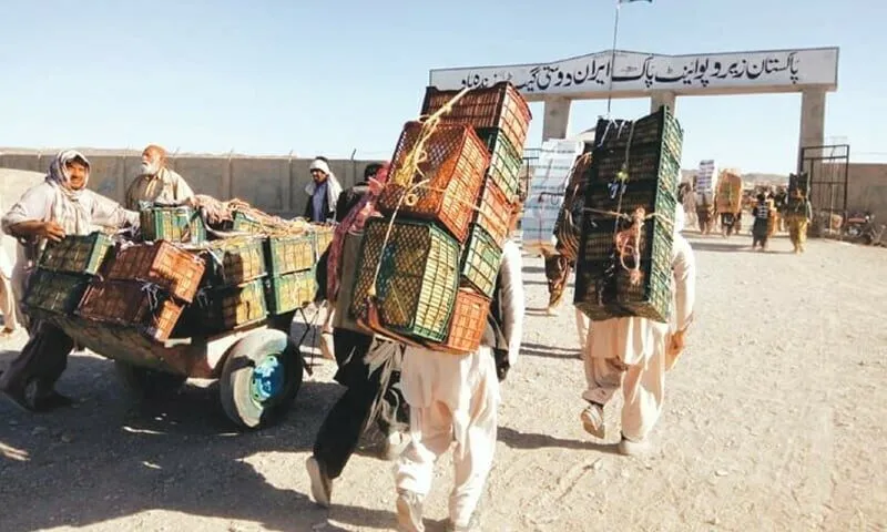 Traders carrying crates across the Iran-Pakistan border gate at Taftan