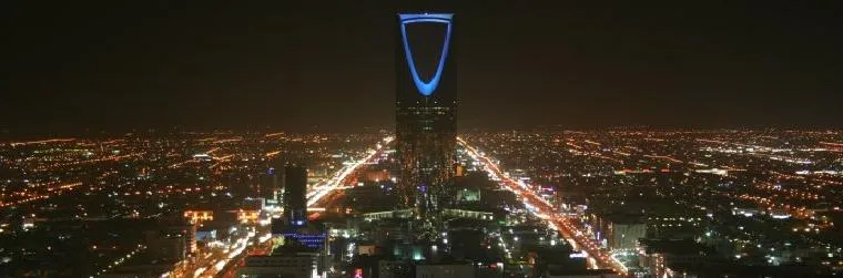 Night aerial view of the Riyadh skyline with the Kingdom Centre tower illuminated in blue; generic file photograph.