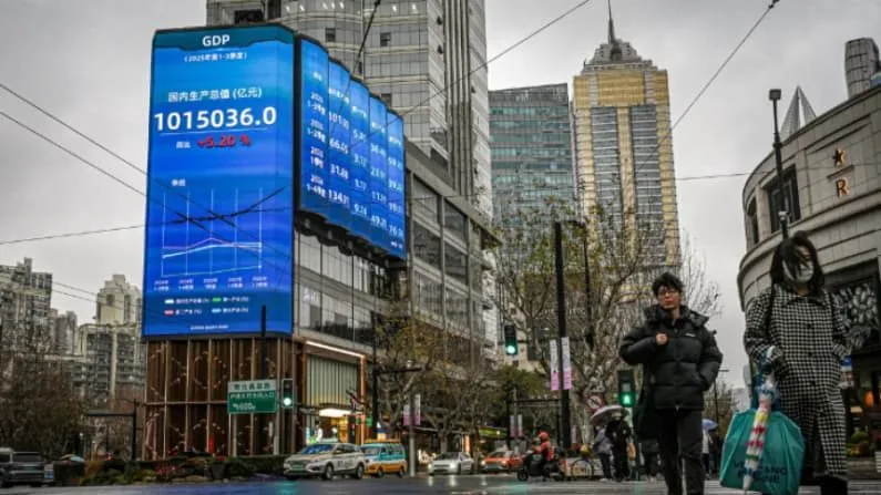 Pedestrians pass a large public display showing China's GDP figures on a Chinese city street