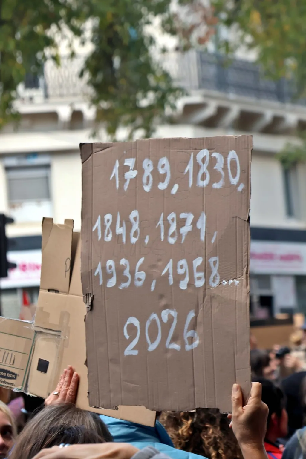 A protester holds a placard listing French uprising dates at the 17 October 2026 Paris demonstration