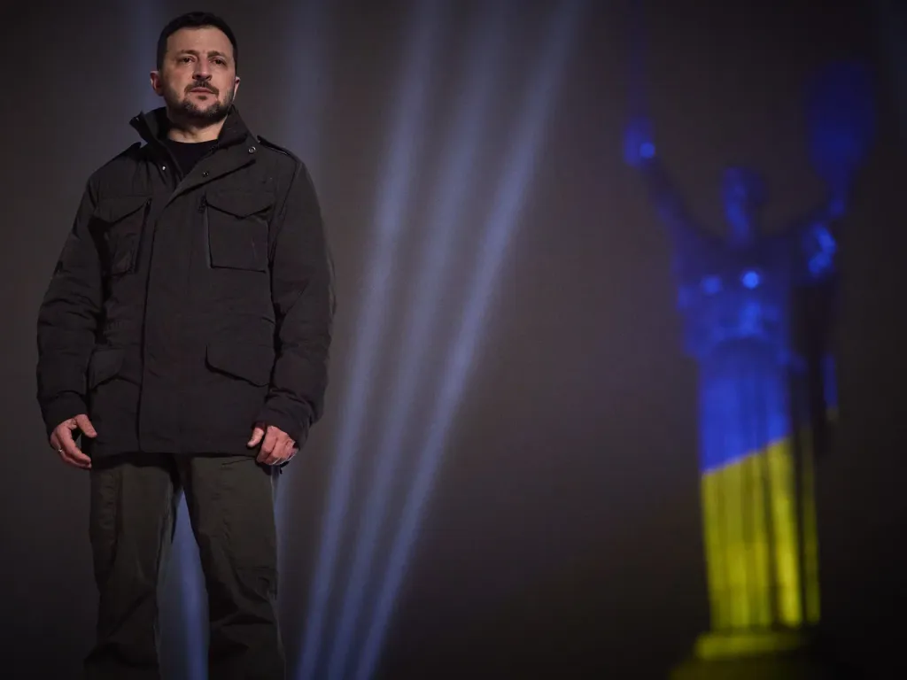 Ukrainian President Volodymyr Zelenskyy in Kyiv on 31 December 2024, with the Motherland monument lit in blue and yellow behind him.