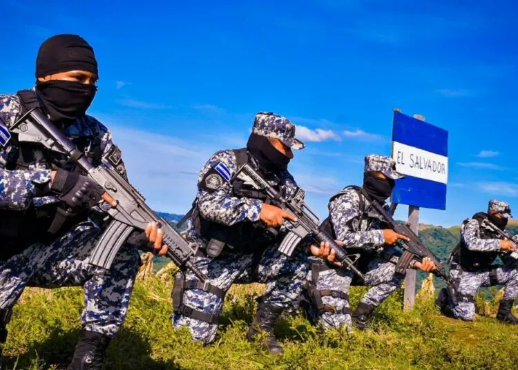 Armed Salvadoran soldiers in camouflage uniform training near an El Salvador flag