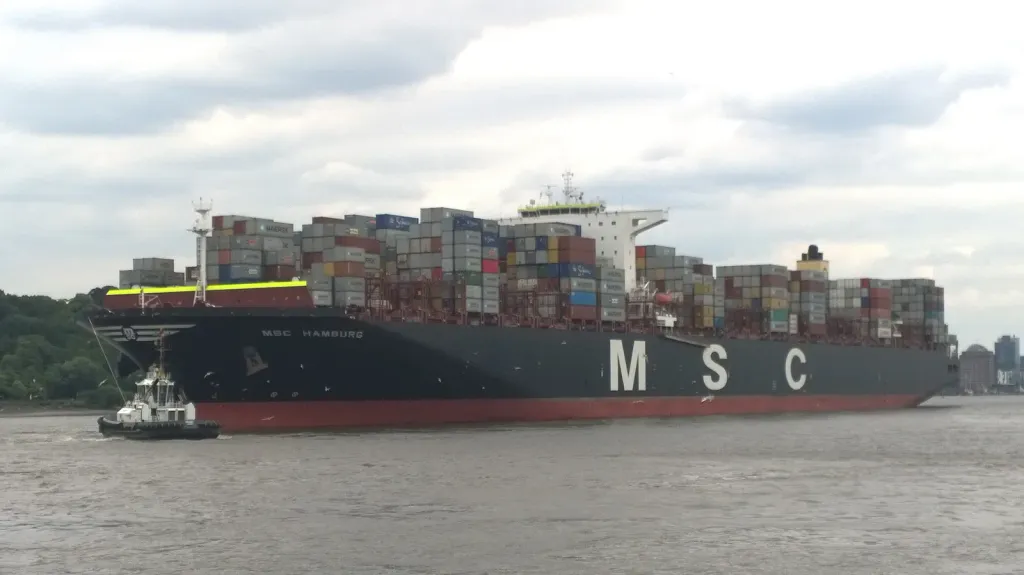Container ship MSC Hamburg fully laden with shipping containers, guided by a tugboat on the river Elbe