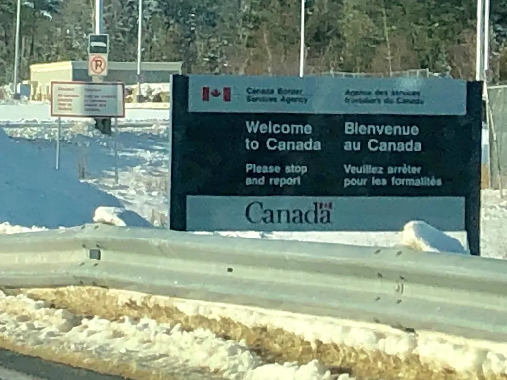 A snow-covered Canada Border Services Agency sign reading 'Welcome to Canada' at the US-Canada border crossing from Calais, Maine to St. Stephen, New Brunswick