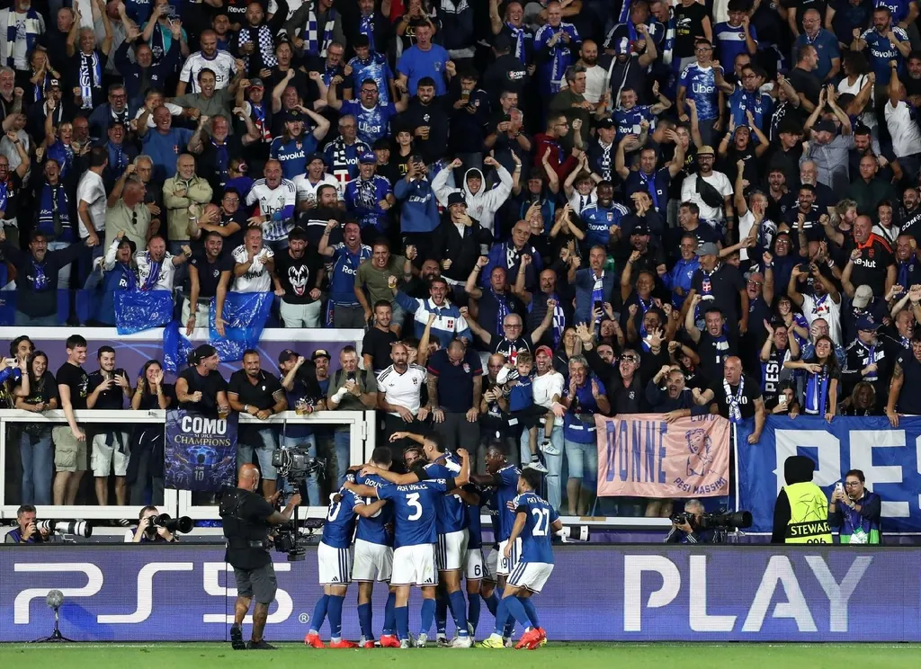 Como players in blue kits celebrate a goal before home fans in the Champions League