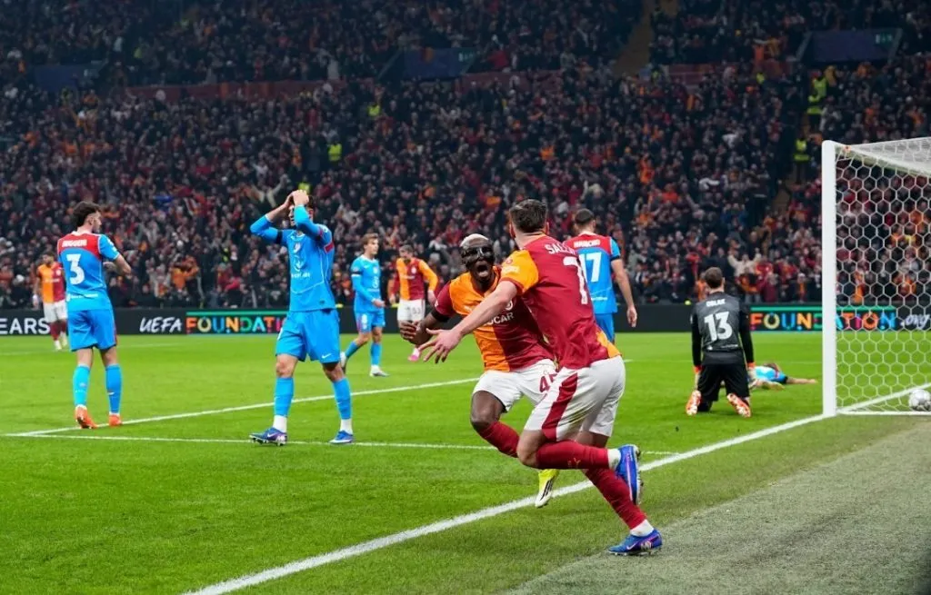 Galatasaray players in orange-red kits celebrate a goal against Lille in the Champions League