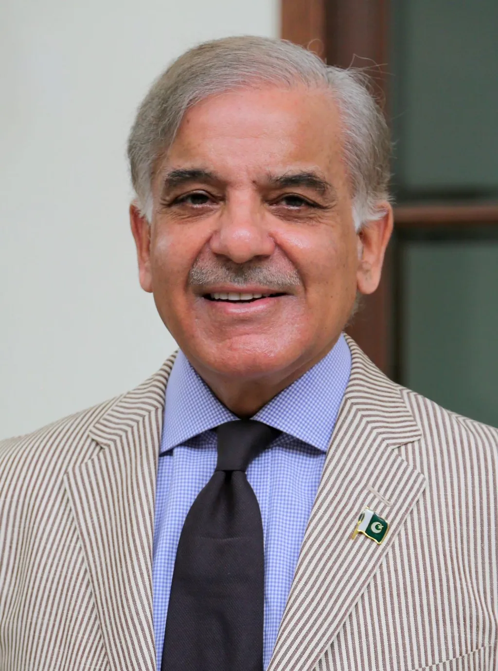 Official 2017 portrait of Pakistani Prime Minister Shehbaz Sharif, smiling, wearing a striped jacket with a Pakistan flag lapel pin.