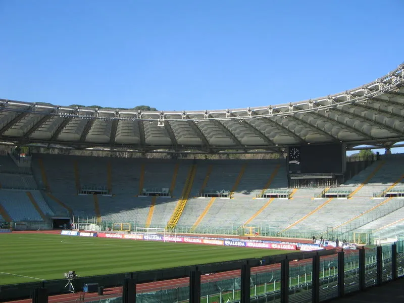 Interior of Rome’s Stadio Olimpico, its distinctive ring-shaped roof arching over empty stands above the athletics track and pitch