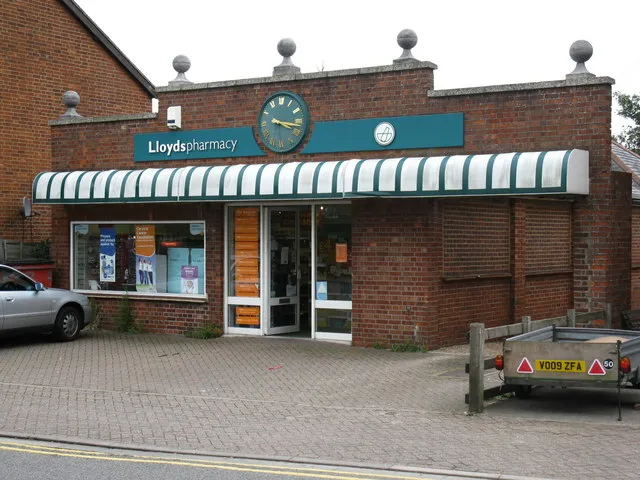 A Lloyds pharmacy shopfront in Binfield, Berkshire: brick facade, green signage and a striped awning over the windows