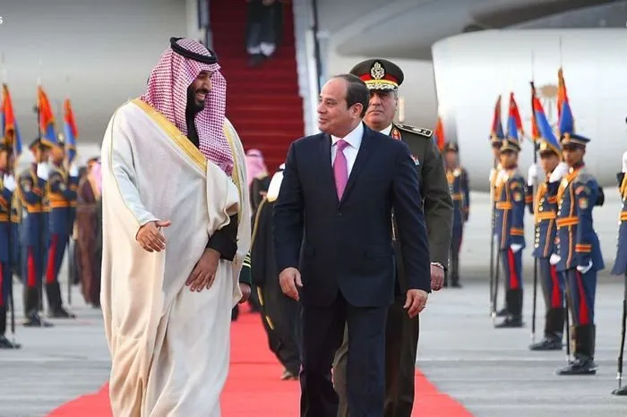 Egypt's President Abdel Fattah el-Sisi walking with a Saudi leader on a red carpet at an airport arrival ceremony.