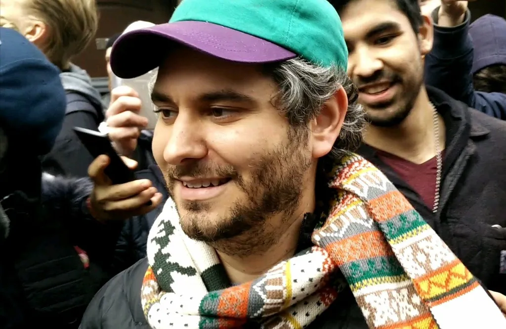 YouTuber Ethan Klein, photographed in 2017, smiling in a crowd wearing a teal and purple cap