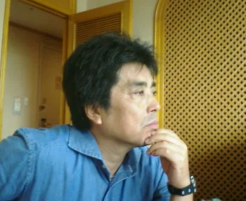 Japanese novelist Ryu Murakami in 2005, wearing a blue denim shirt, hand resting on his chin