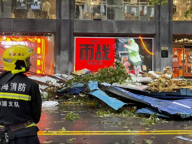 A firefighter in a yellow helmet stands amid typhoon debris strewn across a shopping street