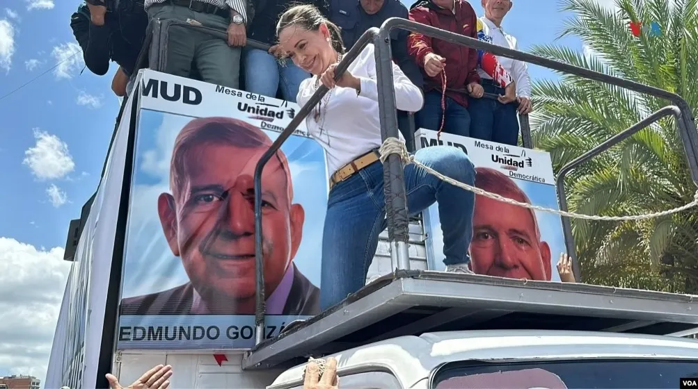 María Corina Machado atop a rally truck at an opposition protest in Venezuela, with MUD banners and supporters (file photo, August 2024)