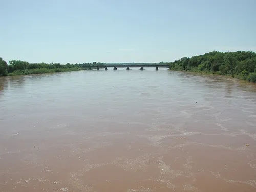 File photo: a muddy US river running high in flood stage beneath a bridge, with submerged floodplain trees on both banks