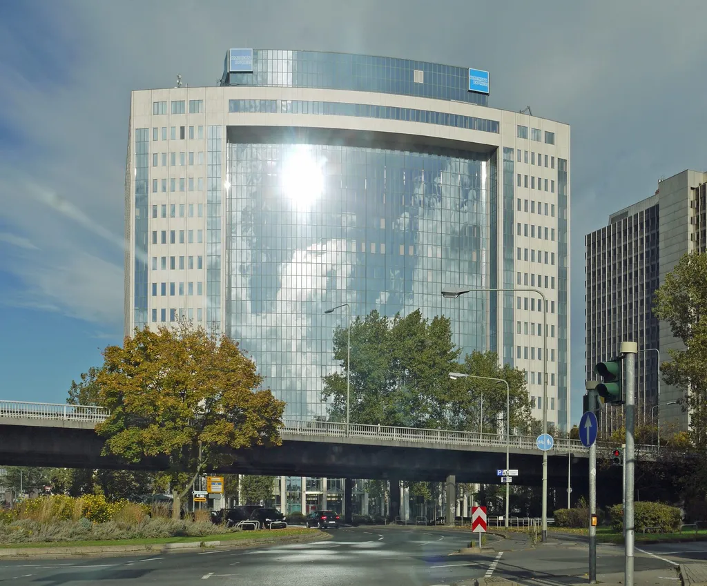 The American Express Germany headquarters building in Frankfurt, a glass-and-stone office tower with blue American Express rooftop signs.