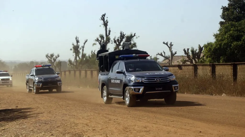 Nigerian police vehicles patrol a dirt road in northern Nigeria