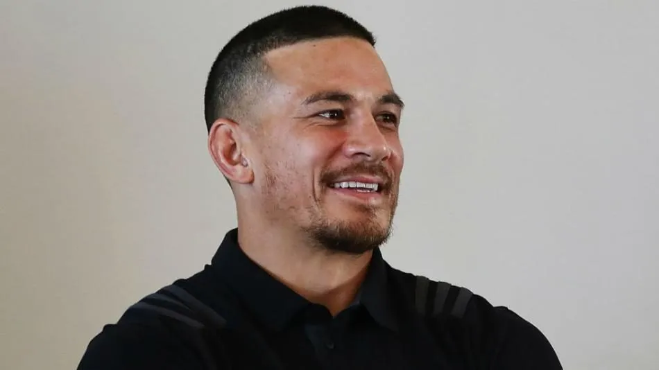 Sonny Bill Williams smiling during an interview in a black polo shirt