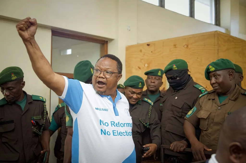 Tanzania opposition leader Tundu Lissu raises a fist while escorted by prison officers