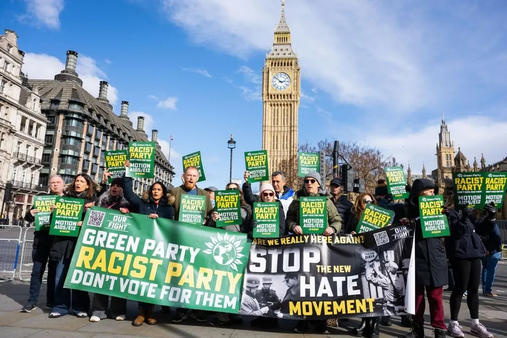Protesters outside Parliament hold signs reading Green Party racist party, do not vote for them