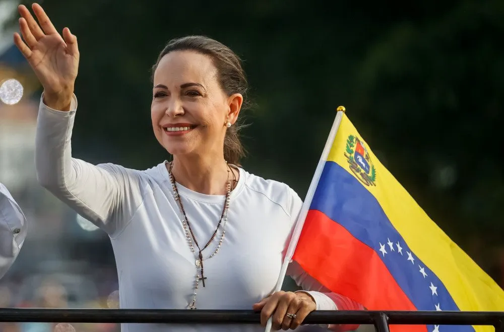 Maria Corina Machado waving while holding a Venezuelan flag